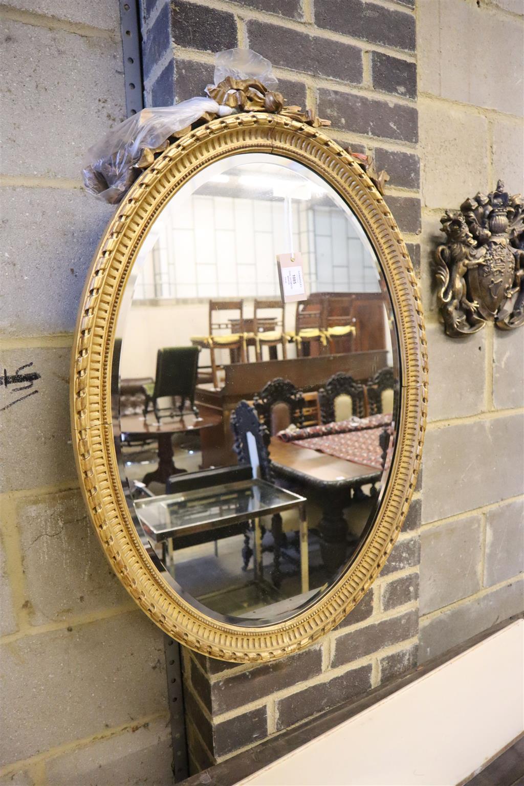 A 19th century oval giltwood mirror with tied-ribbon and floral mounts (faults), 60 x 84cm